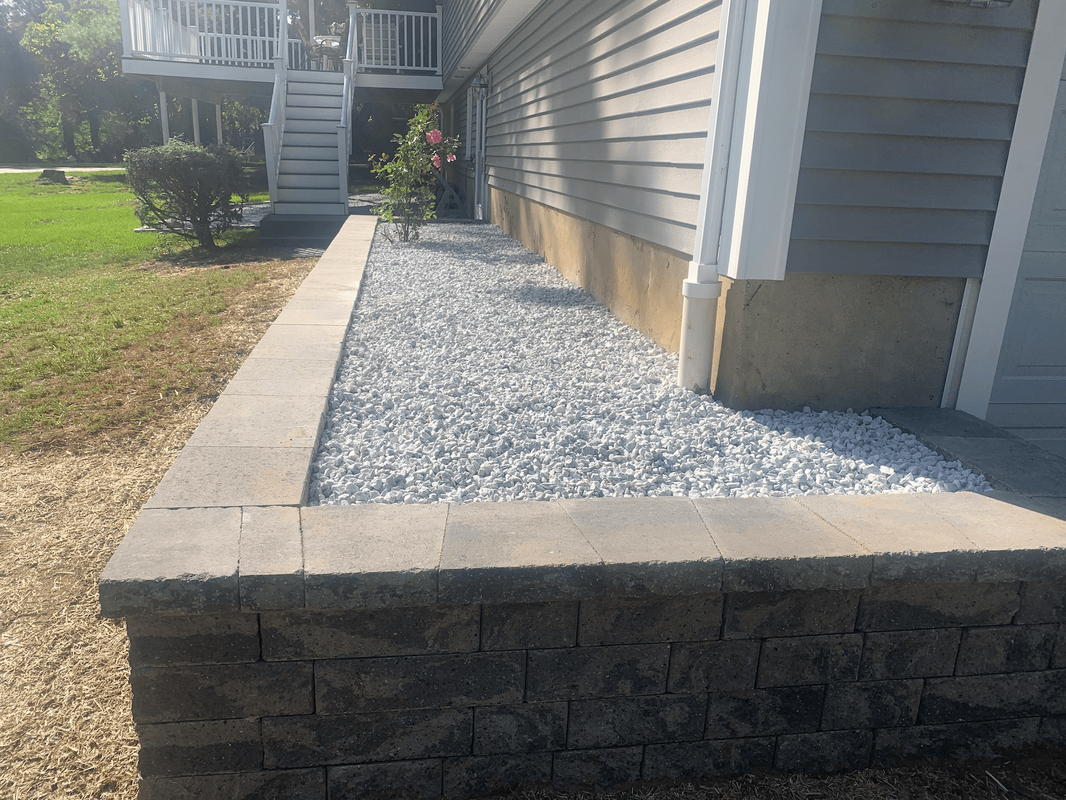 block wall planter with capstones filled with white landscape rocks