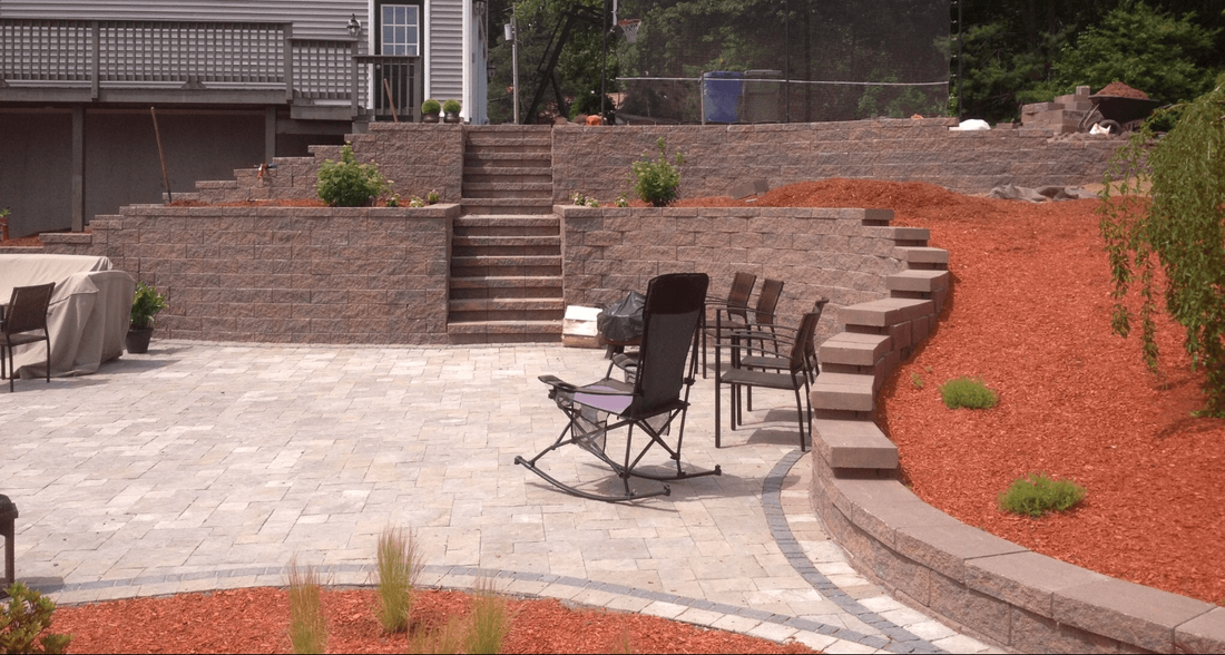 Paver patio, block retaining wall, red mulch with shrubs