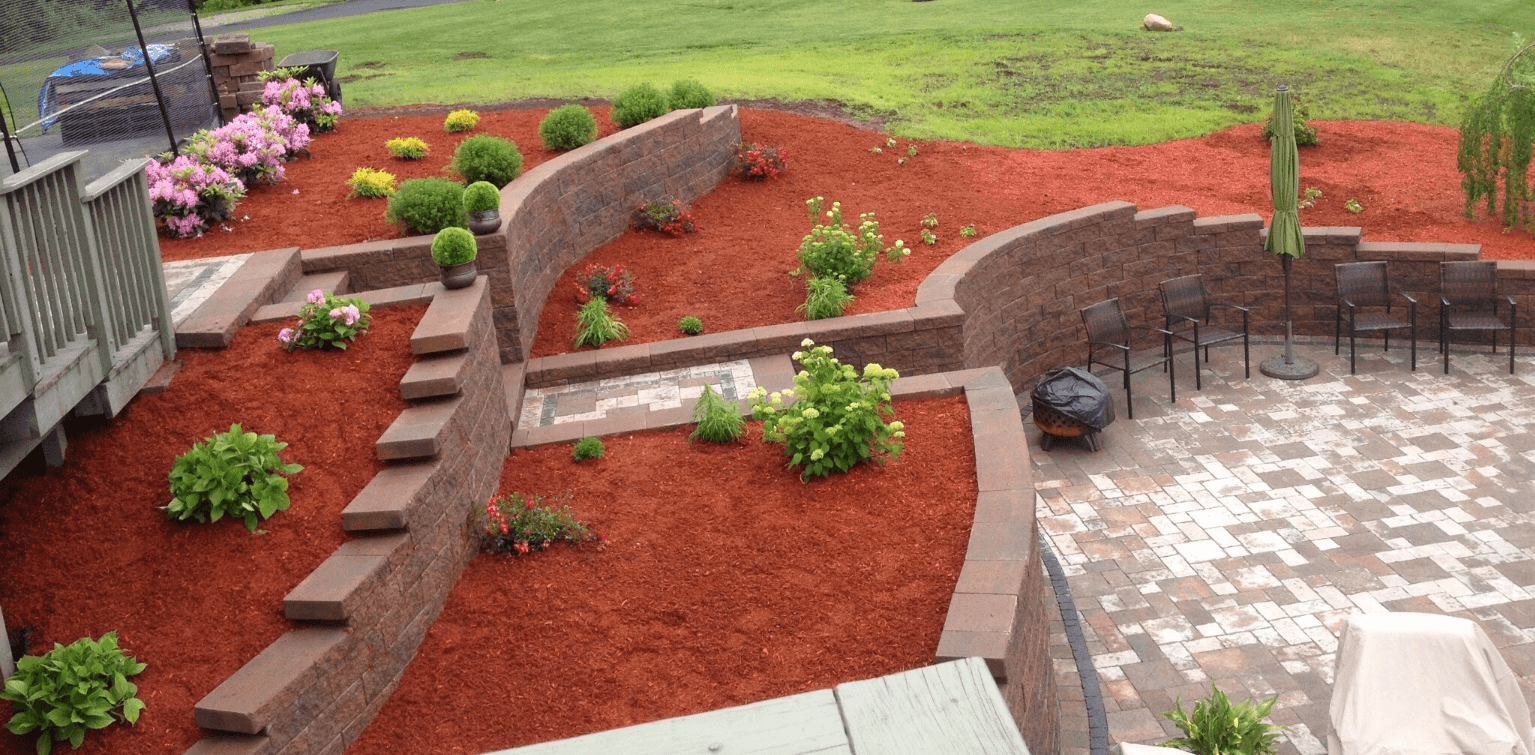 large planter areas with red mulch, and small shrubs and flowers.  
