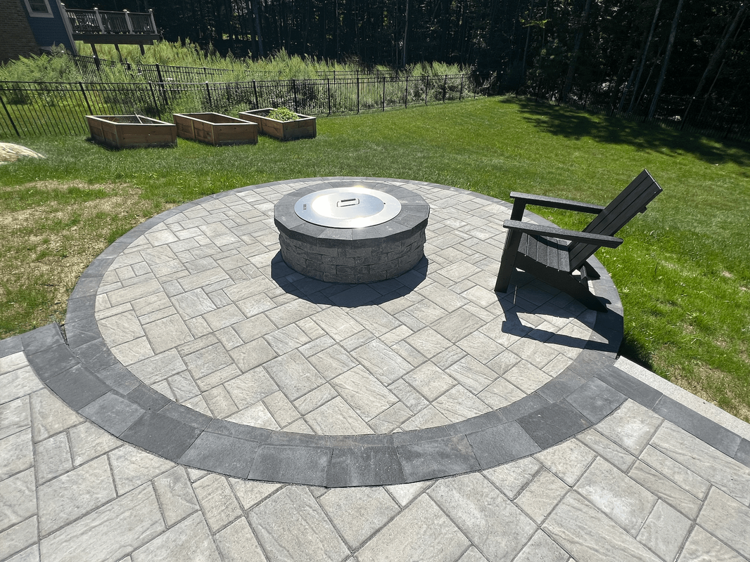 Fire pit with gray pavers with a dark grey pavers circle connected to a paver patio